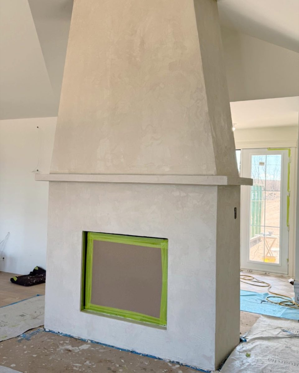 Cheminée finie en microbéton beige, surface continue sans joint du foyer jusqu'au plafond