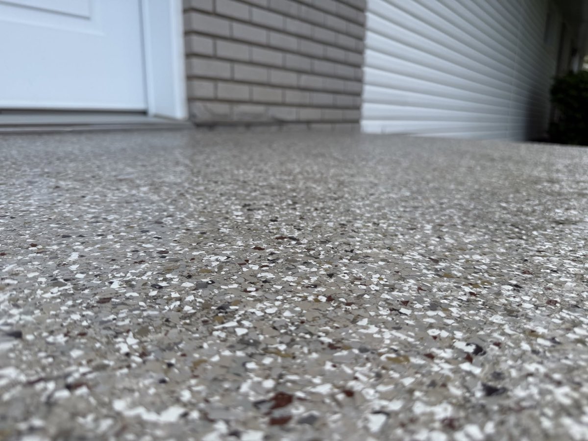 Gros plan d'un plancher époxy à flocons de vinyle, porte de garage en arrière-plan
