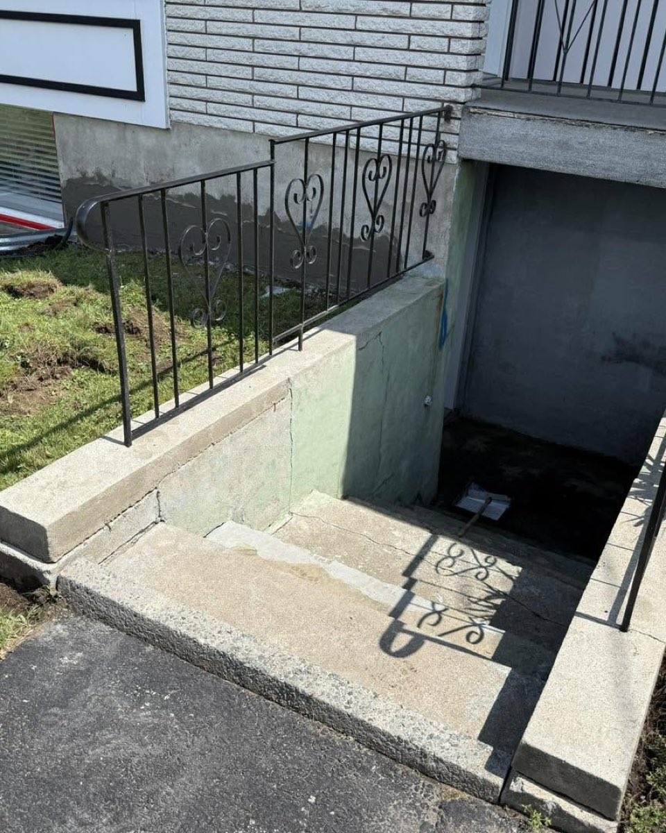 Descente d'escalier de sous-sol en béton exposé aux marches grenues, avant travaux