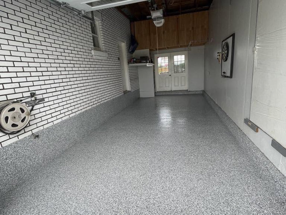 Le même garage après travaux, plancher époxy gris à flocons et mur de brique repeint en blanc