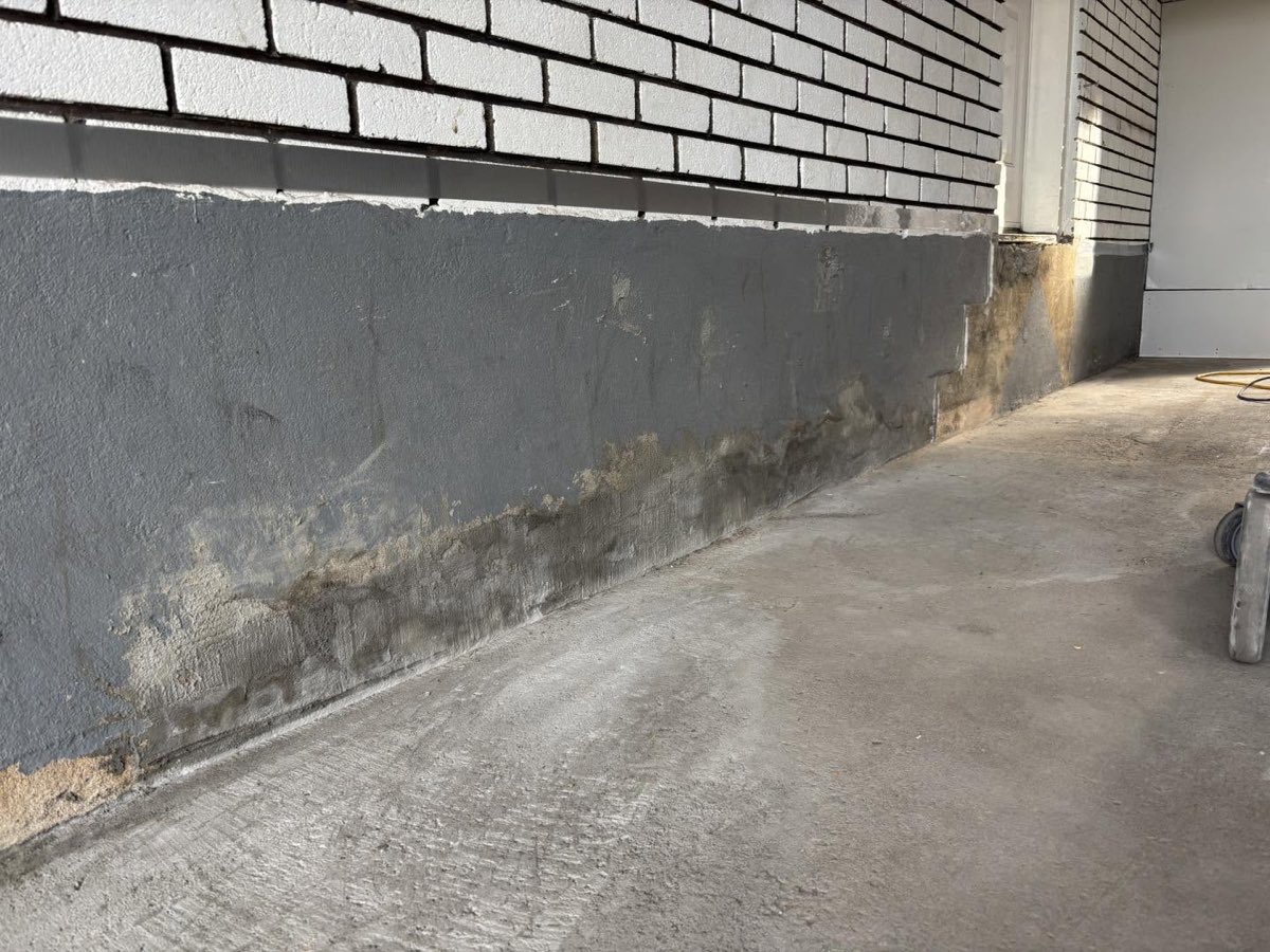 Garage avant travaux, dalle de béton brute et bas de mur abîmé