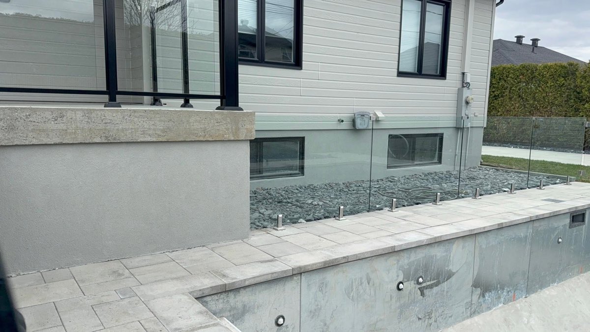 Muret de terrasse après finition, surface lisse et uniforme gris clair avec garde-corps de verre