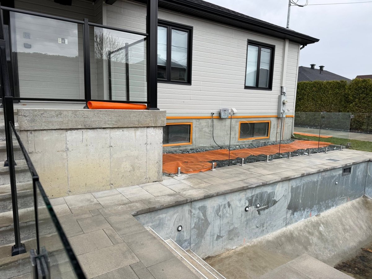 Avant les travaux, muret de terrasse en béton brut avec garde-corps de verre