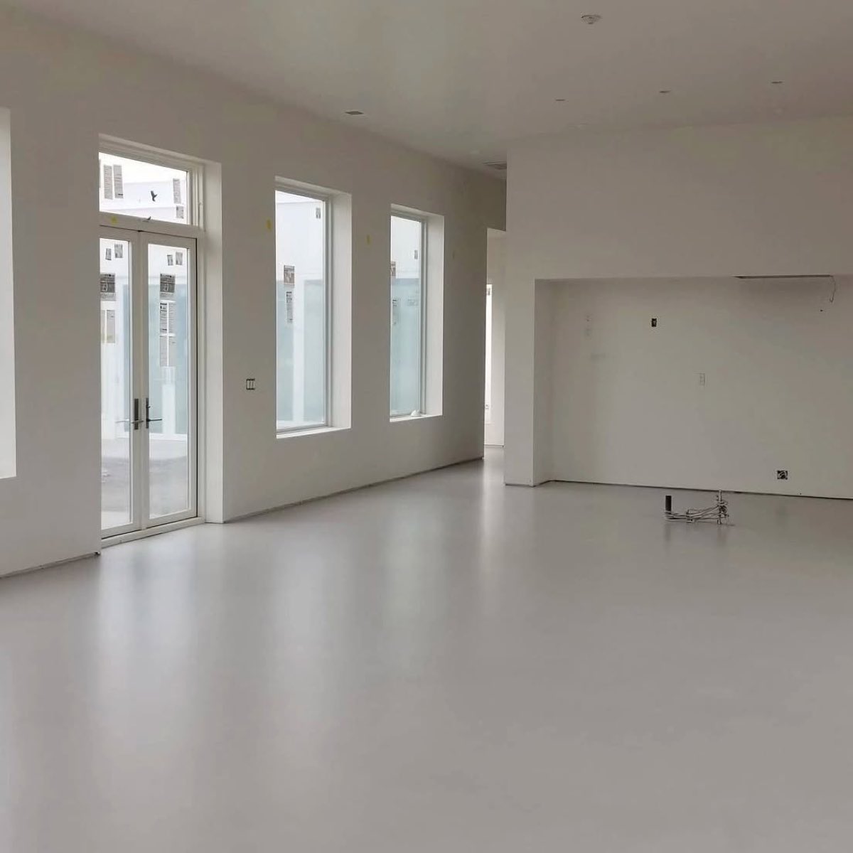 Grande pièce vide avec plancher de microbéton clair continu, sans joint d'une extrémité à l'autre
