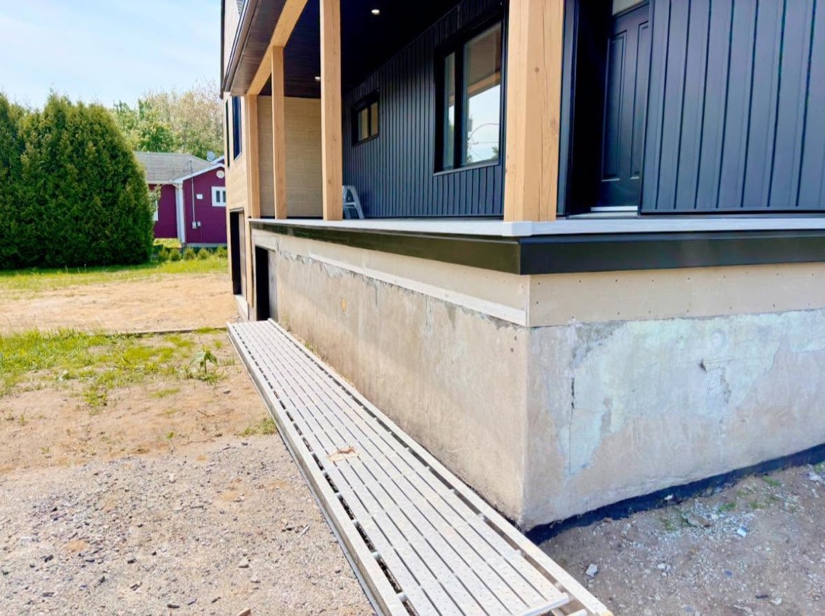 Avant les travaux, solage de maison neuve en béton brut avec drain de surface