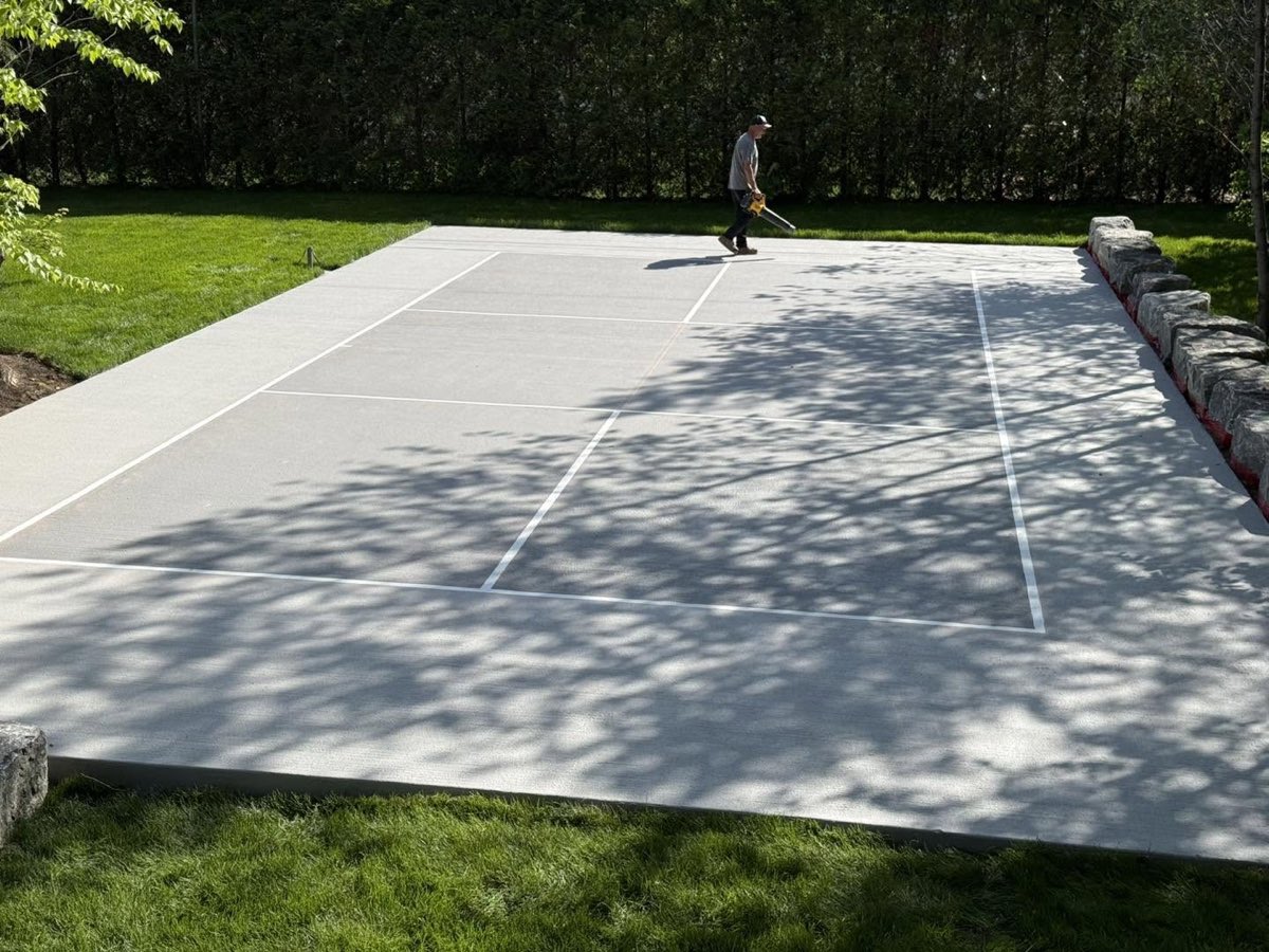 Dalle de béton neuve dans une cour arrière, lignes de terrain tracées à la craie avant les couches de couleur