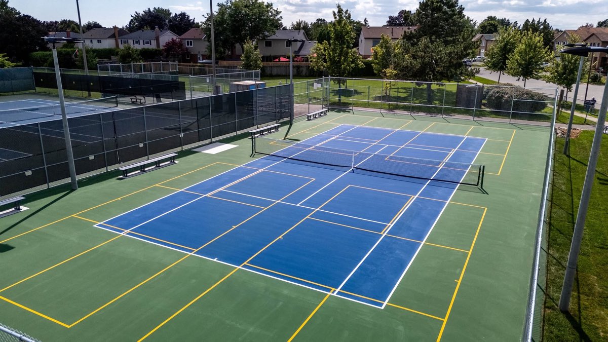 Terrains de pickleball à surface acrylique bleue et verte, vus de haut, clôturés et lignes fraîchement tracées